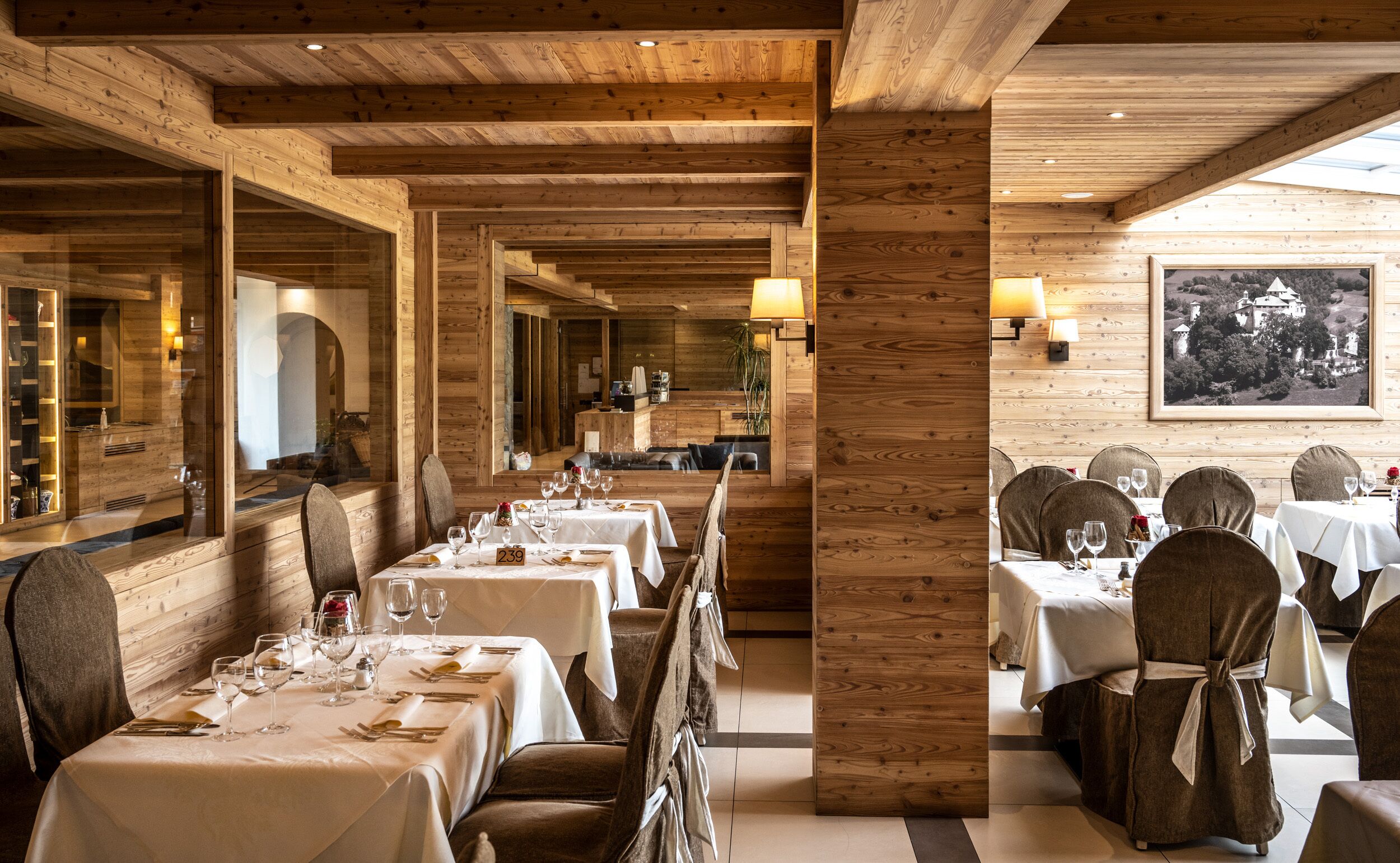 A restaurant with wooden interiors, multiple dining tables, and chairs.