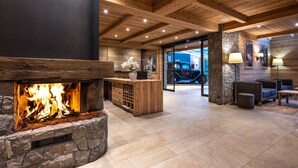 A lobby with a stone fireplace, wooden ceiling, and a reception desk.