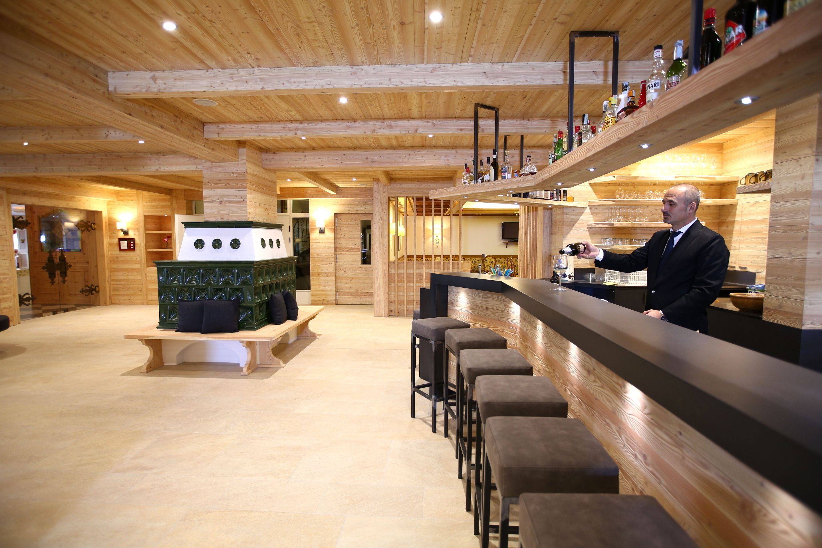 Een bar met houten balken, een toonbank en krukken.