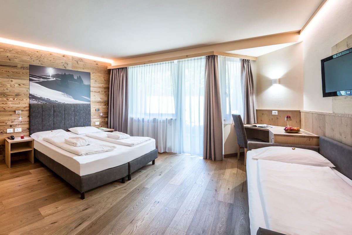A hotel room with a wooden wall, a bed, a desk, and a TV.