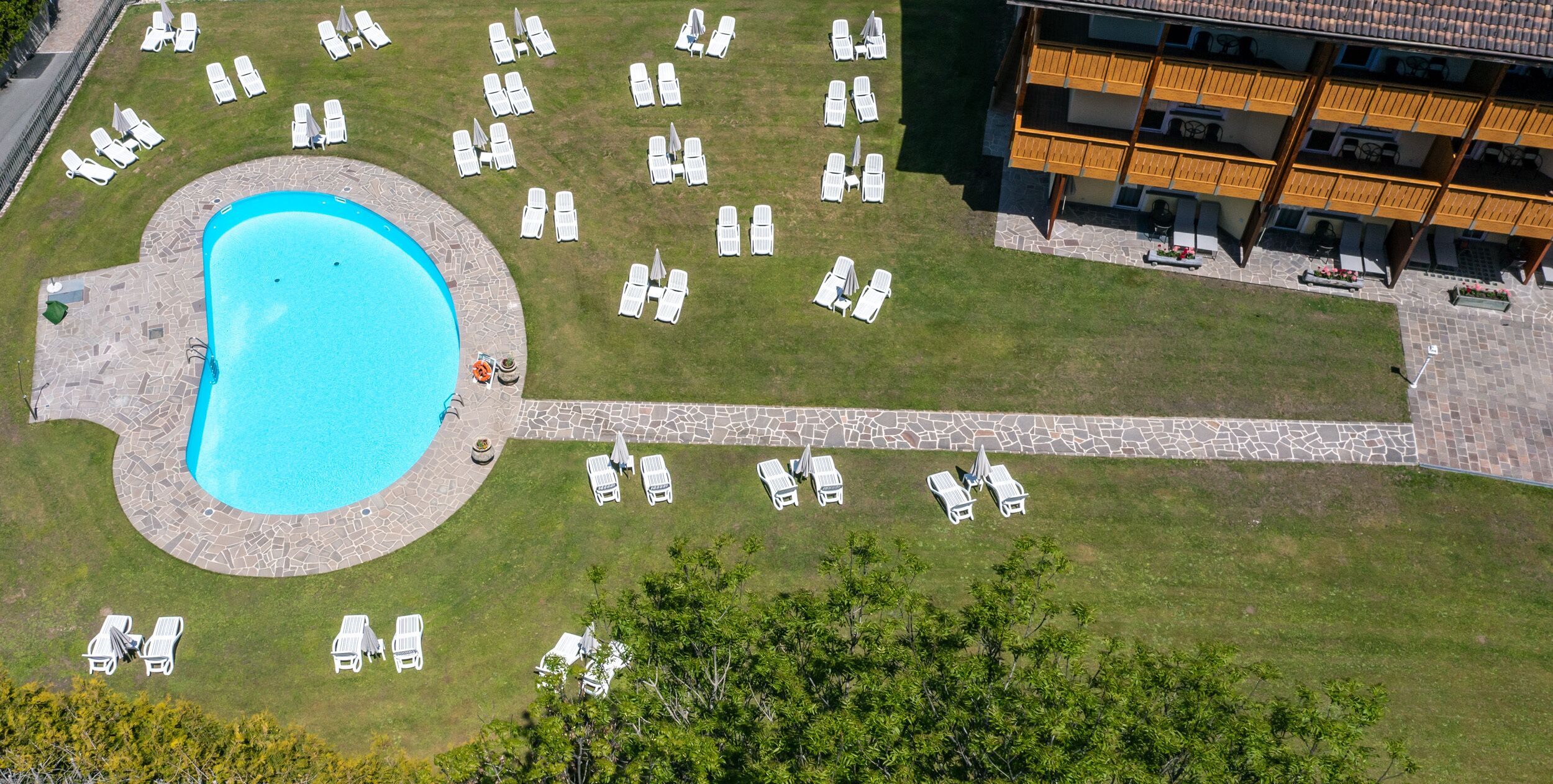 An aerial view of a hotel with a swimming pool surrounded by lounge chairs and a stone deck.