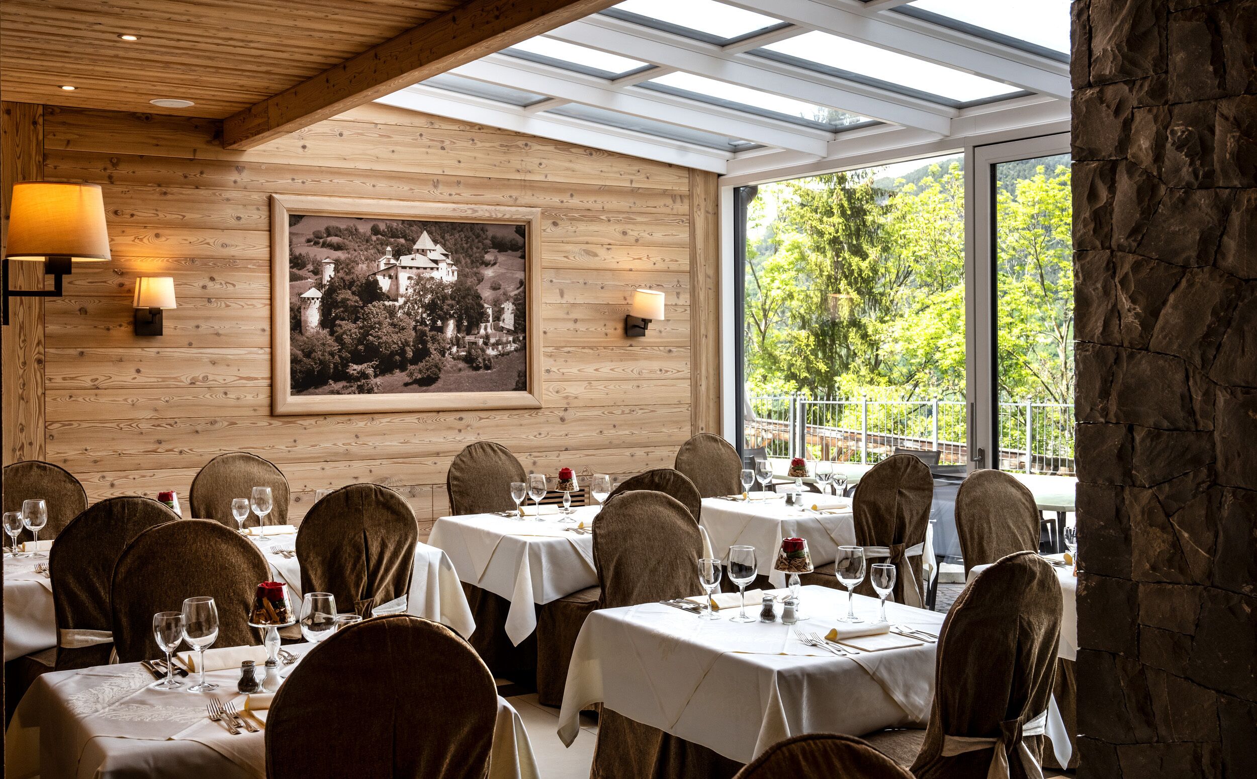 A restaurant with wooden walls, a large framed picture, and a view of greenery outside.