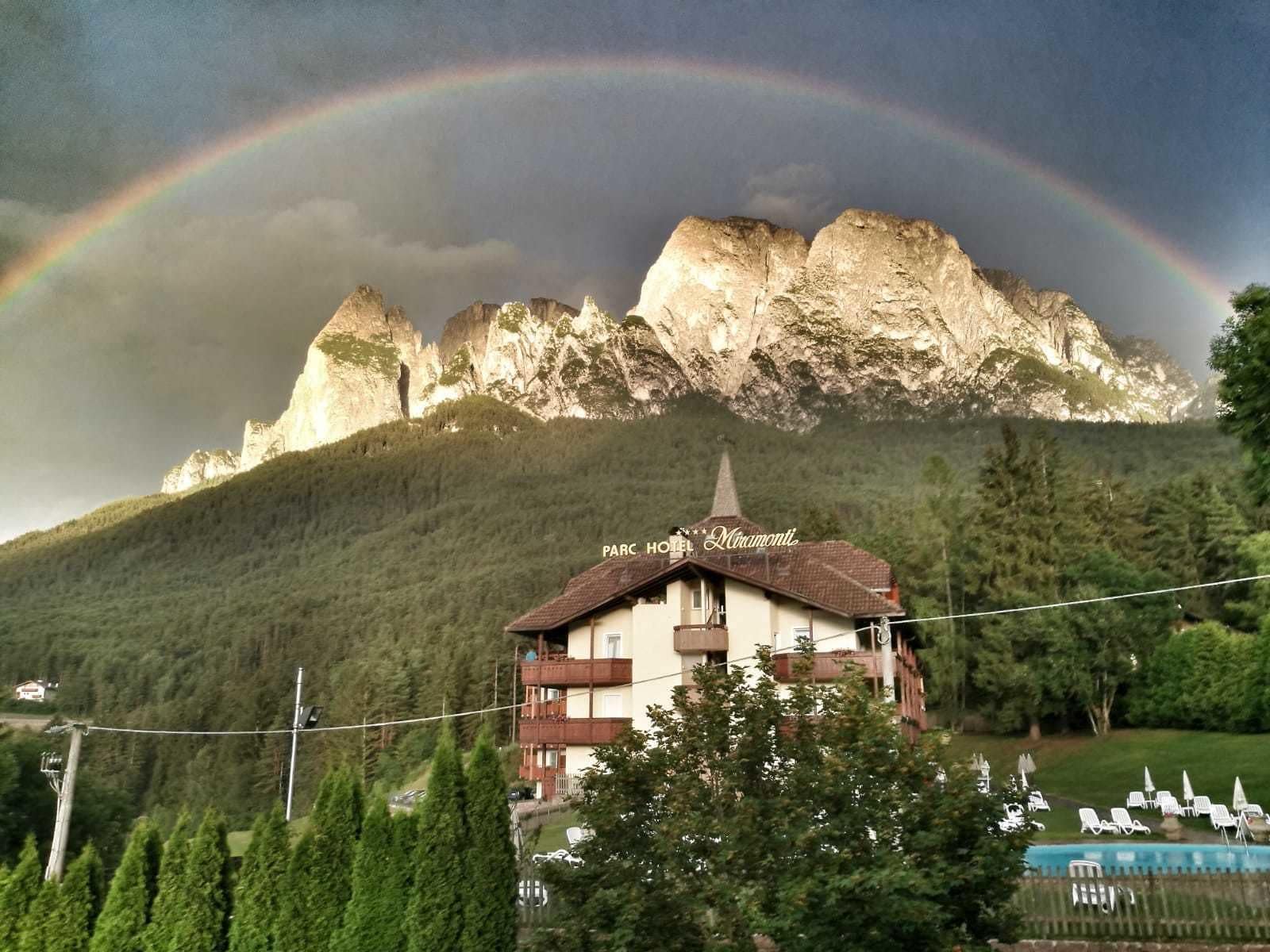 Un hotel con montañas al fondo y un arcoíris.