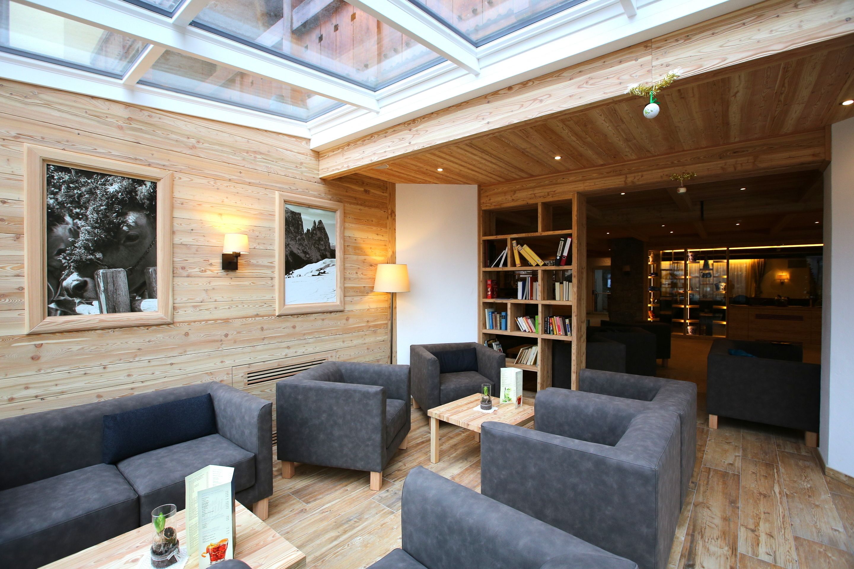 Une pièce chaleureuse avec un plafond en bois, une lucarne, un canapé, une table basse et une bibliothèque.