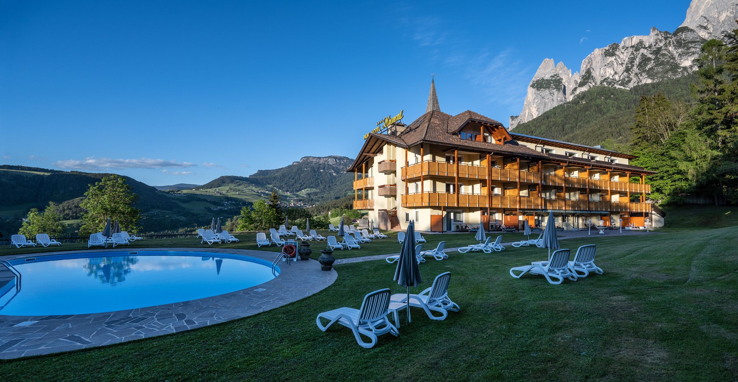Ein Hotel mit Pool, Liegestühlen und einer Bergkulisse.