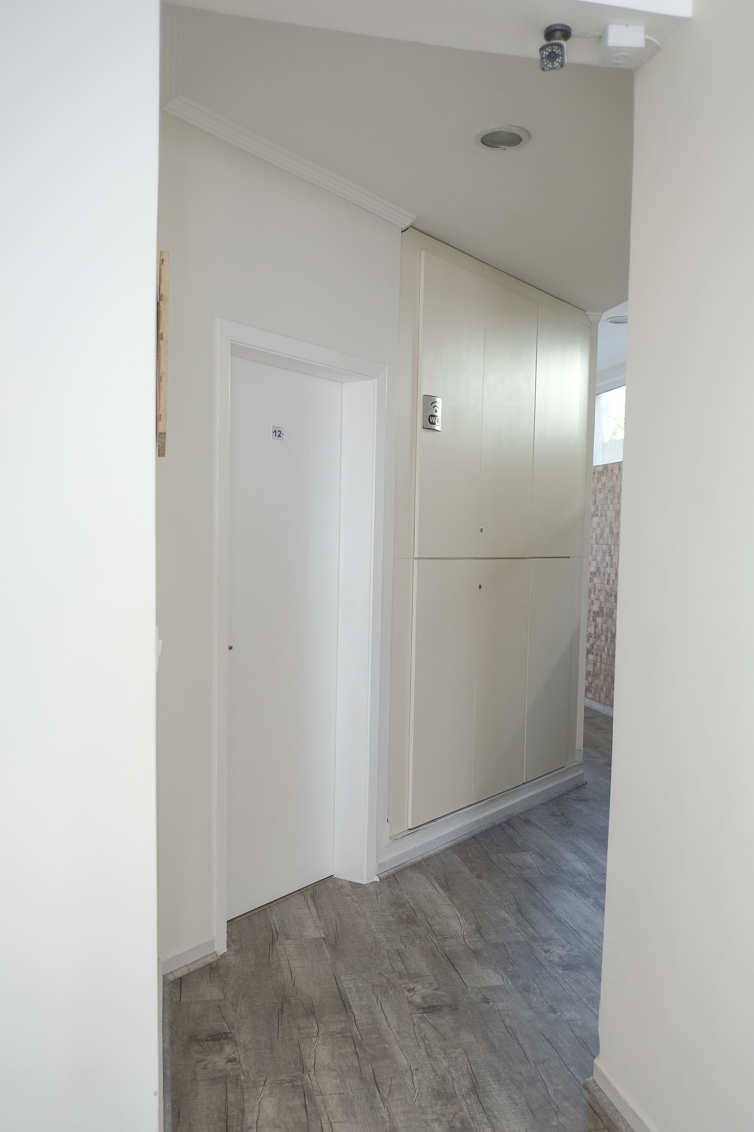 A hallway with a white door marked '12', a white wardrobe, and a wooden floor.