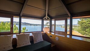 A room with a view of a lake and a bridge, featuring a bed with pillows and a lamp. - Pazo da Merced (Neda)