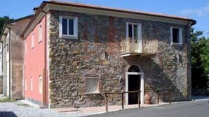 Un edificio de piedra con fachada roja, un balcón y una entrada pequeña.