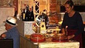 Una cocina con una persona preparando comida, una encimera con distintos utensilios de cocina y una pared con una ventana.