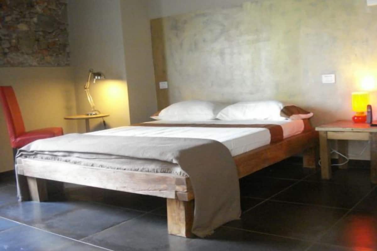 Ein Schlafzimmer mit einem Bett, einem Sessel, einem Nachttisch und einer Lampe.
