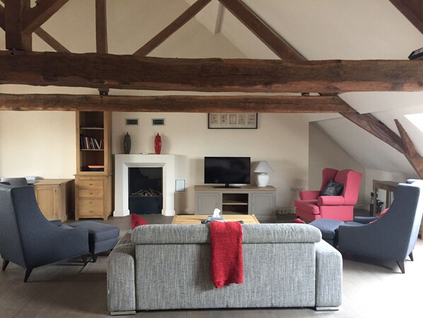 A loft-style living room with exposed wooden beams, a fireplace, a television, and modern furniture. - Hotel Royal Astrid Aalst (Aalst)