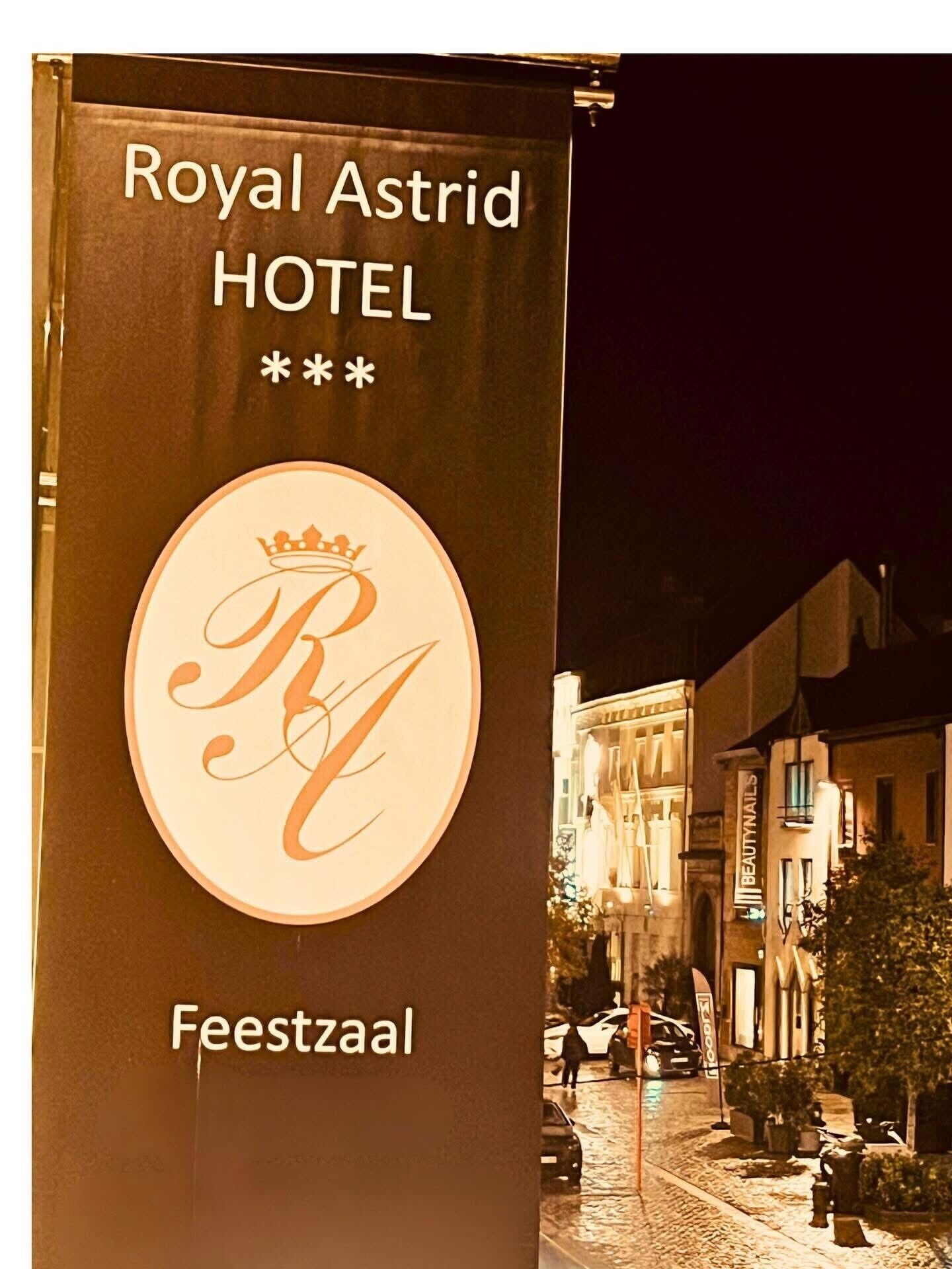 Un banner del Hotel Royal Astrid en Feestzaal, con una corona y el logotipo con monograma.
