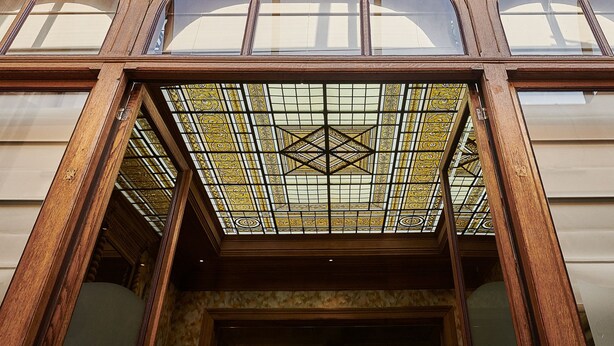 A building with a large, ornate wooden facade, multiple arched windows, and a stained glass skylight. - Hotel Royal Astrid Aalst (Aalst)