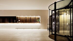 A spacious lobby with a modern reception desk, a seating area, and a glass elevator. - Square Nine Hotel Belgrade-The Leading Hotels of The World (Belgrade)