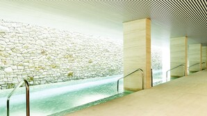 A modern interior with a stone wall, a water feature, and metal railings. - Square Nine Hotel Belgrade-The Leading Hotels of The World (Belgrade)