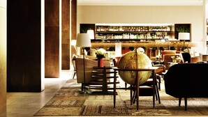 A bar area with a variety of bottles and a globe. There are several chairs and a sofa in the foreground. - Square Nine Hotel Belgrade-The Leading Hotels of The World (Belgrade)