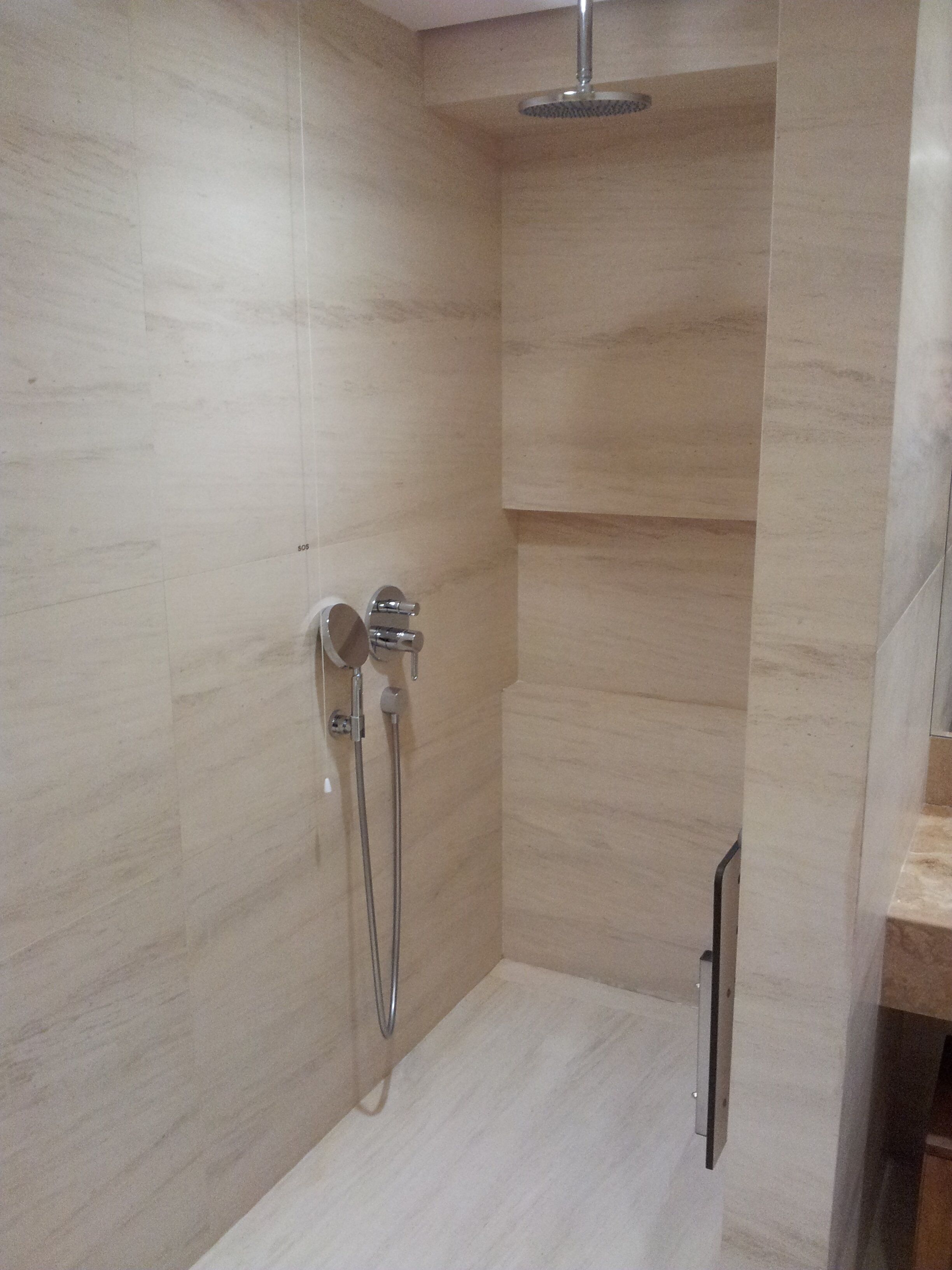 A shower with a handheld showerhead and a wall-mounted faucet.