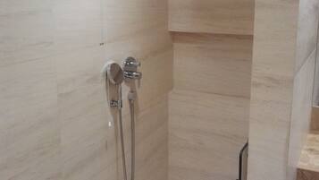 A shower with a handheld showerhead and a wall-mounted faucet.