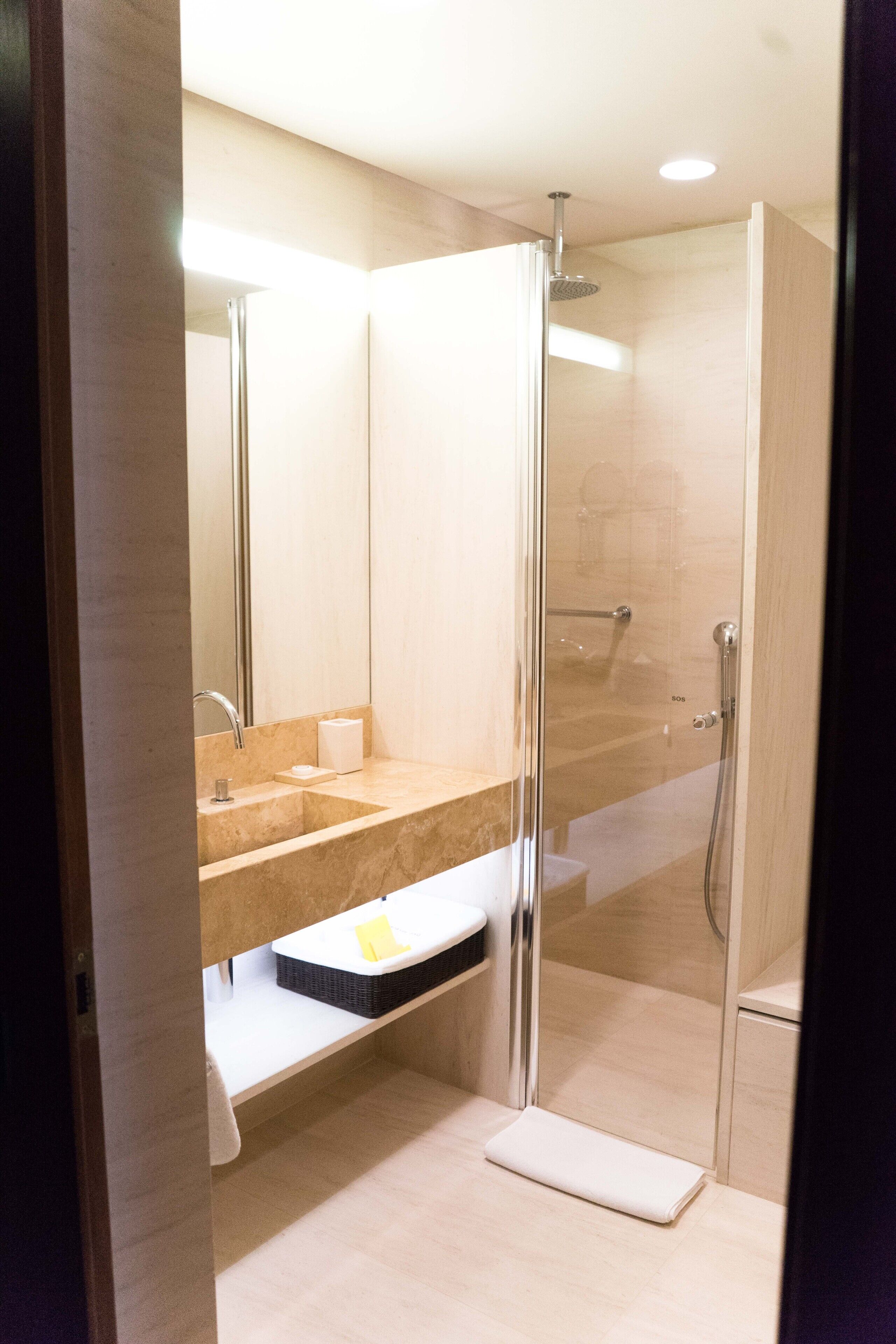 A modern bathroom with a glass-enclosed shower, a sink with a mirror, and a towel rack.