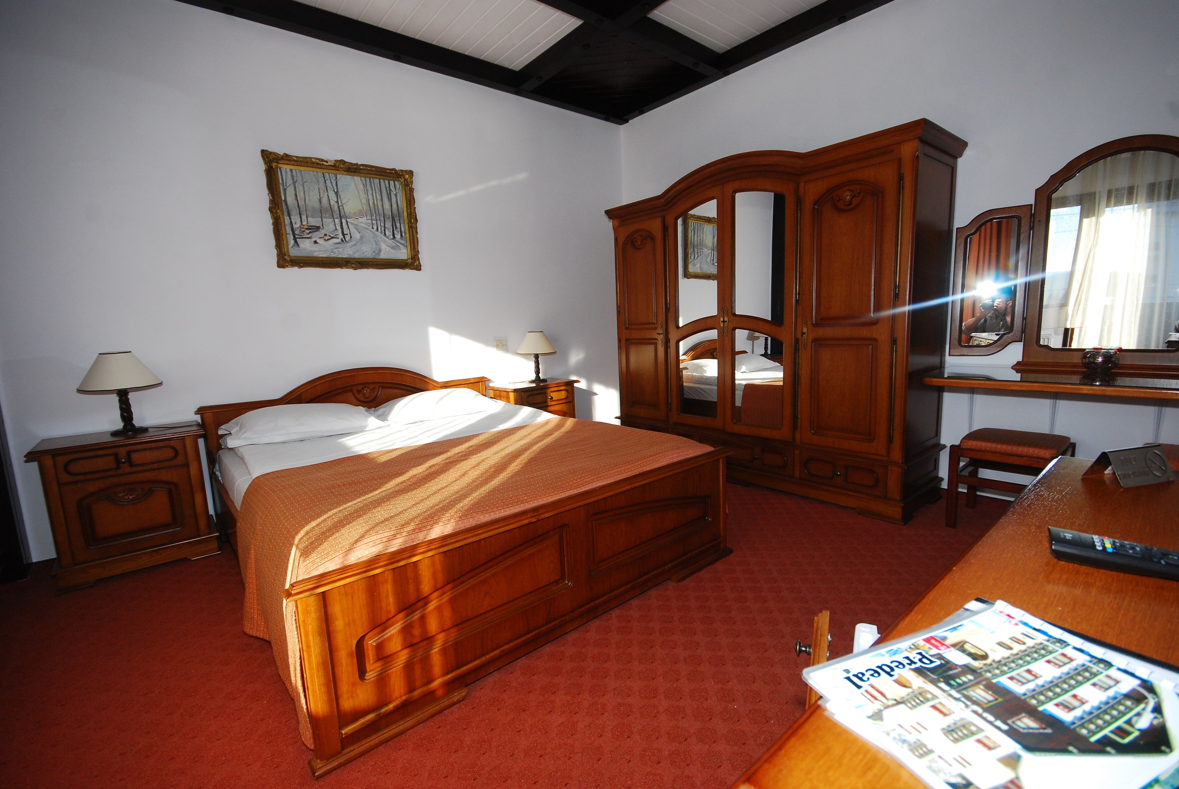 Un dormitorio con una cama de madera, una mesita de noche, un aparador y un espejo.