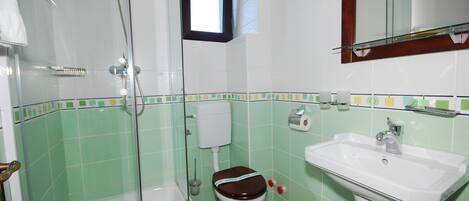 A bathroom with a shower, toilet, and sink.