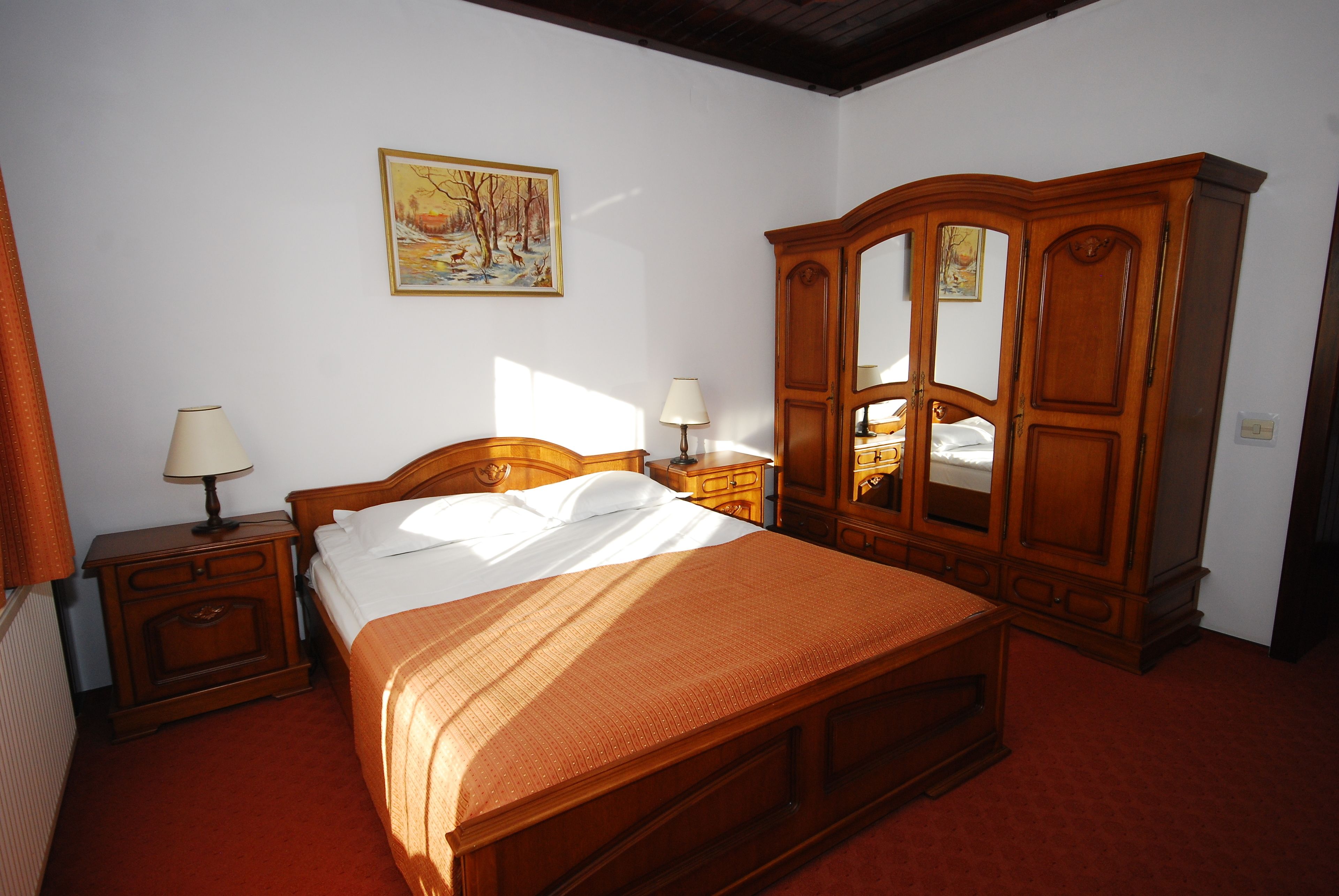 Un dormitorio con una cama de madera, mesitas de noche, un armario y un cuadro en la pared.