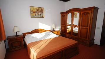 Un dormitorio con una cama de madera, mesitas de noche, un armario y un cuadro en la pared.