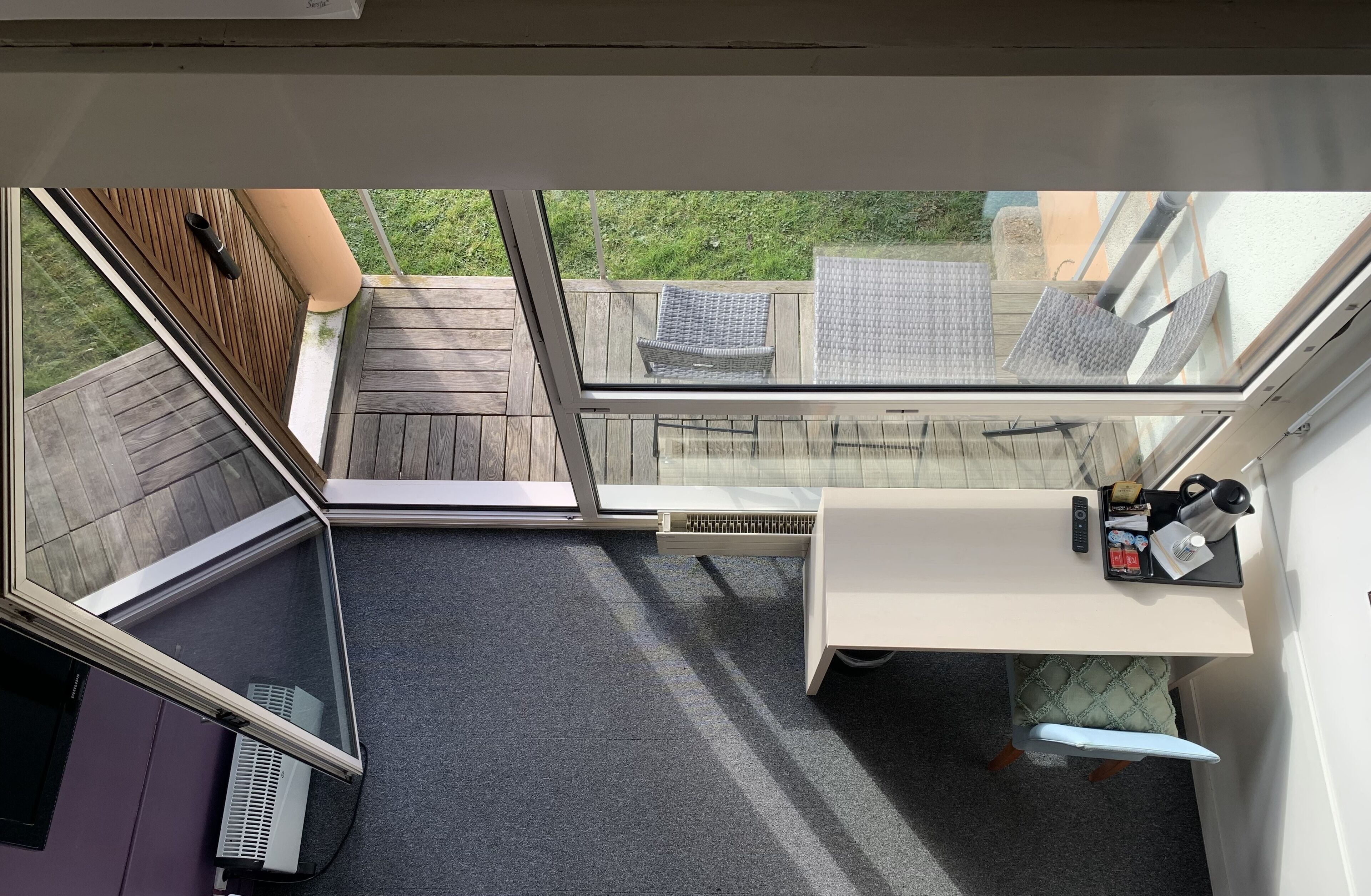 A room with a view of a wooden deck, a small table with a tray, and a chair.