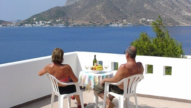 Dos personas sentadas en una mesa con vista a una montaña y al mar.