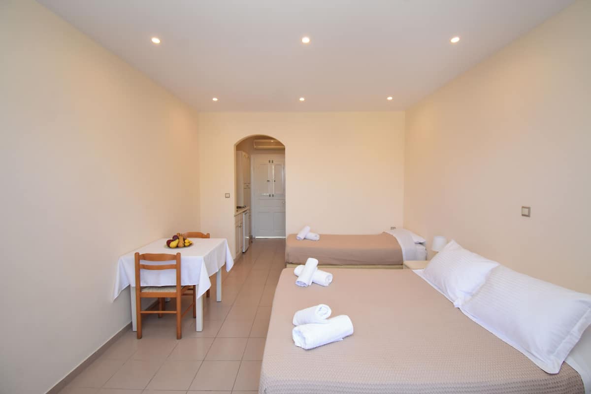 A hotel room with a bed, a small table with a chair, and a dining table.