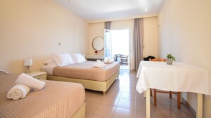 Habitación de hotel con dos camas, una mesa de comedor, una silla, una mesita con un jarrón y vistas al exterior.