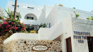 Un edificio blanco con un muro de piedra y un letrero que dice "Apollonia hotel".