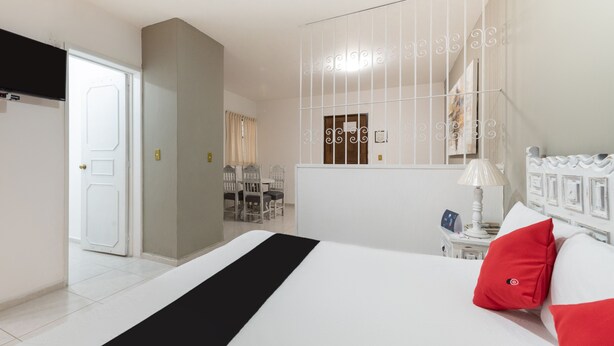 A hotel room with a bed, a desk, and a chair. - Suites Internacional (Zapopan)