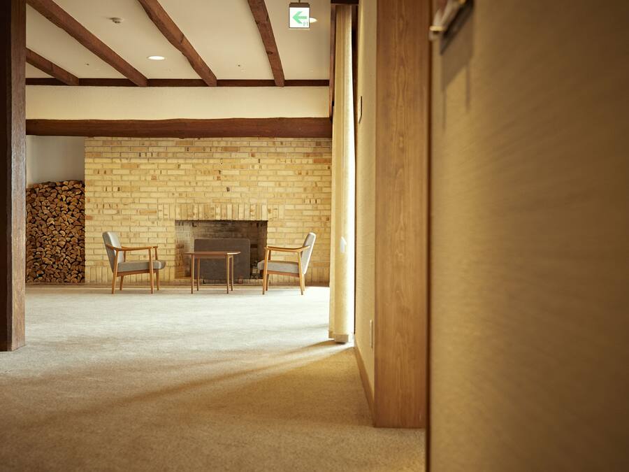 A spacious room with a brick fireplace, two chairs, and a table.