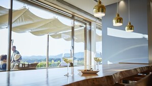 A restaurant with a wooden table, wine glasses, and a plate of food. Large windows offer a view of the outdoors. - Shima Kanko Hotel The Classic (Shima)