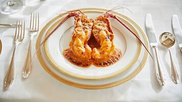 A formal dining table set with a white tablecloth, gold-rimmed plates, and silverware.