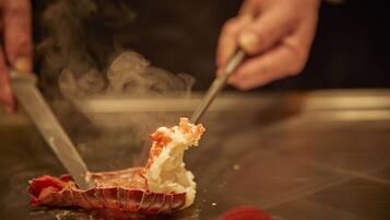 A person cutting a lobster on a table.