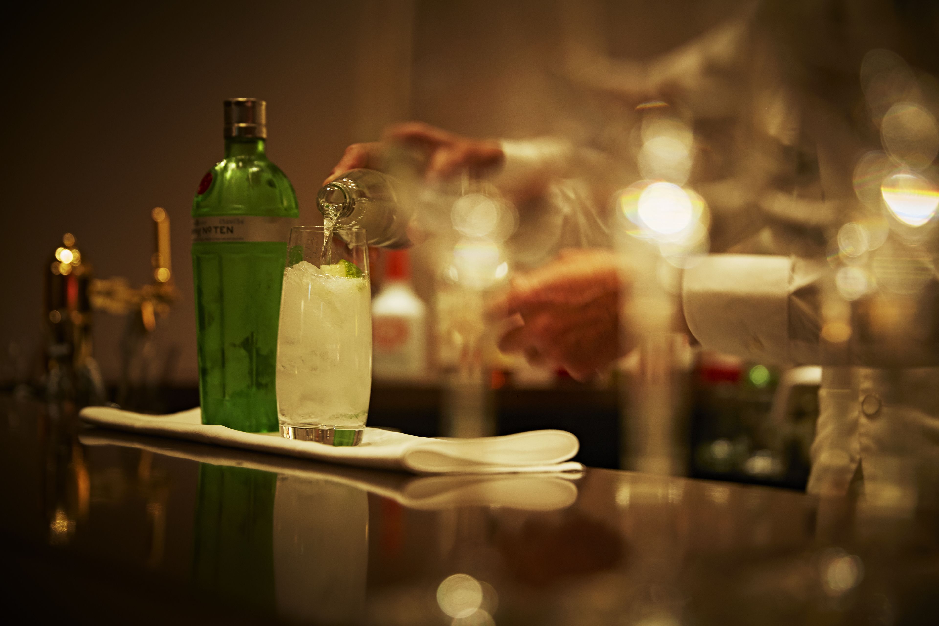 A bar setting with a green bottle and a glass on a white tray.