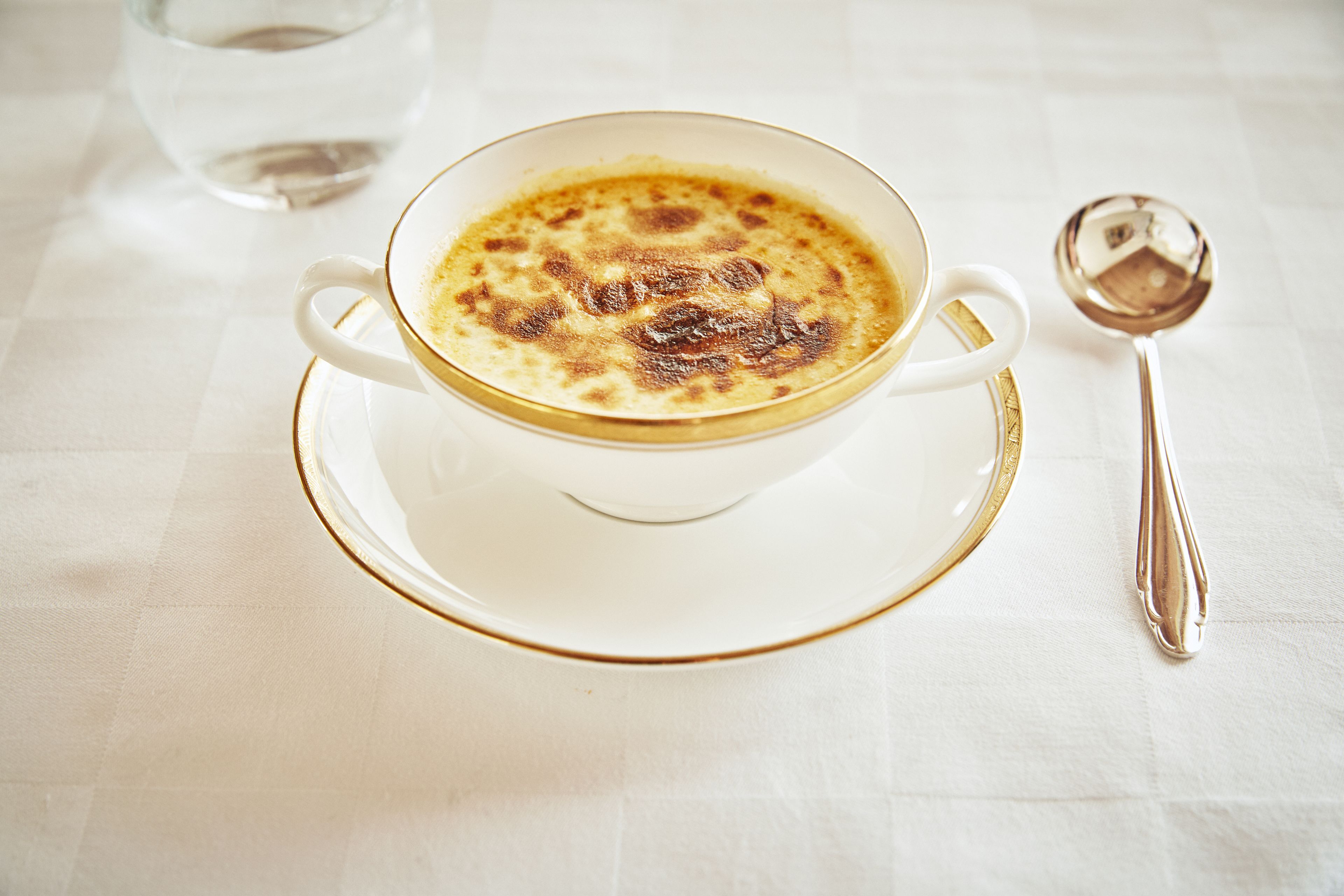 A cup of coffee on a saucer with a spoon beside it.