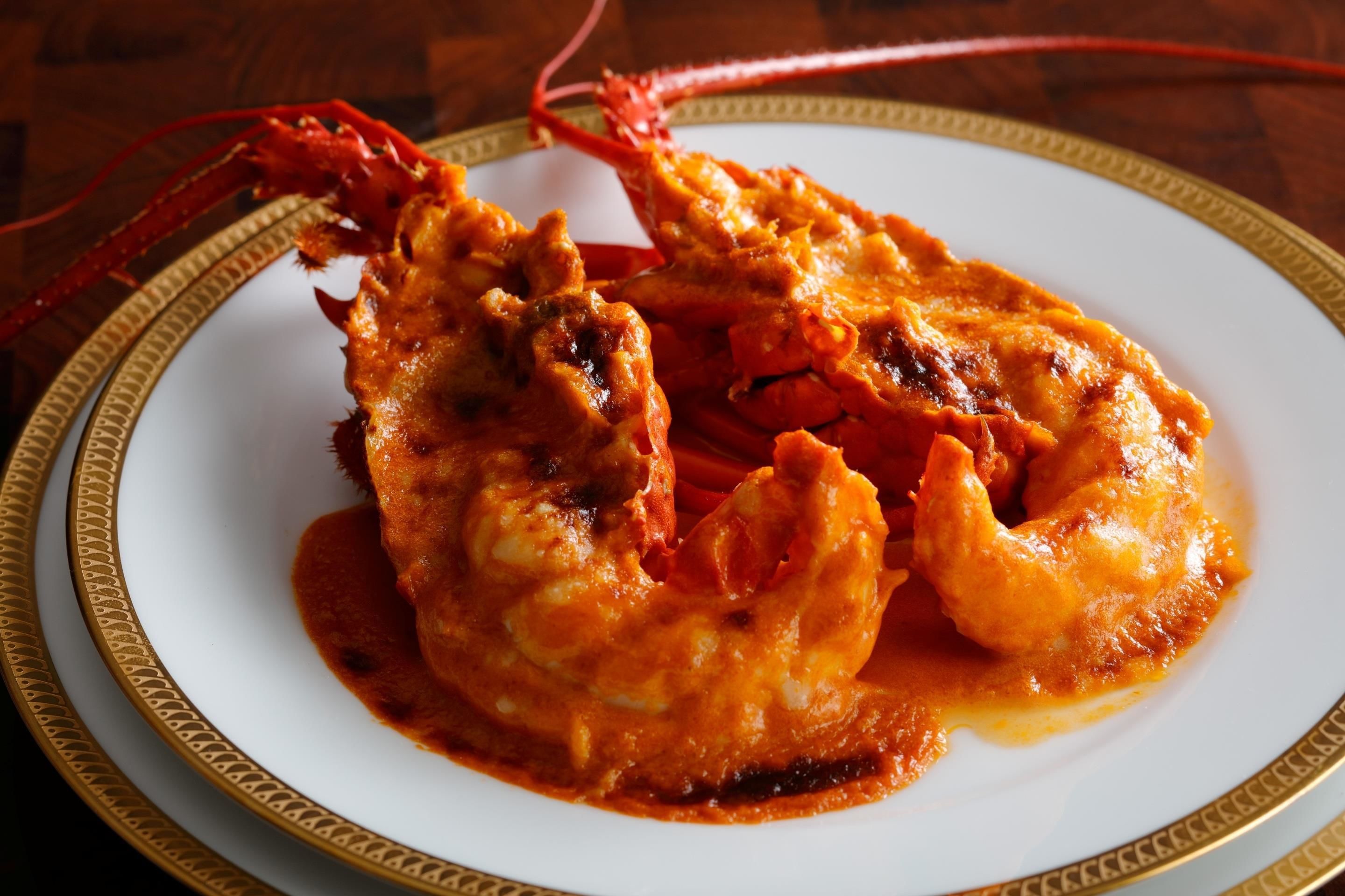A plate of fried seafood with a red sauce, served on a white plate with a gold rim.