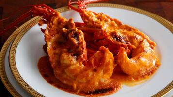 A plate of fried seafood with a red sauce, served on a white plate with a gold rim.