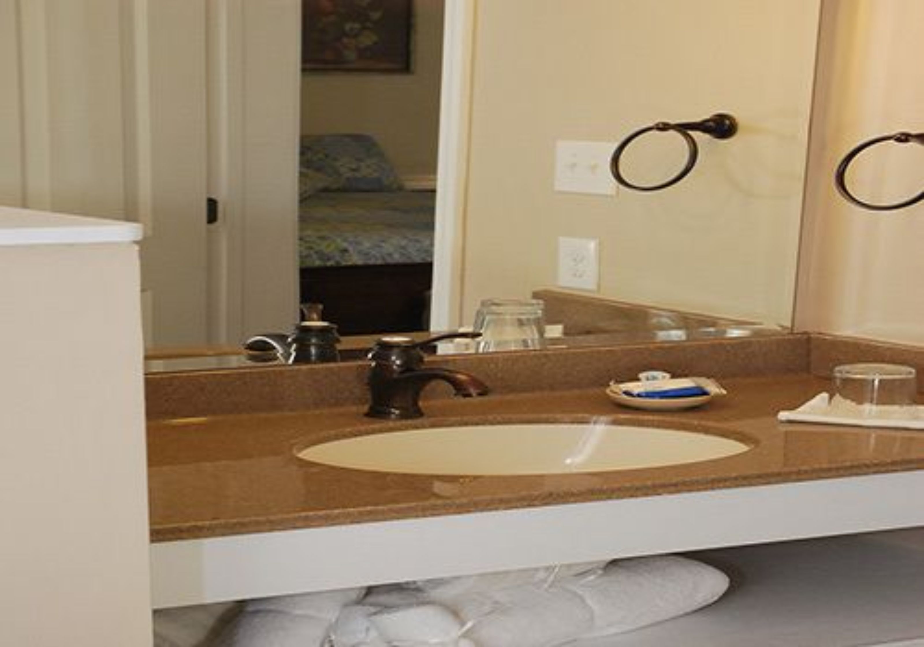 A bathroom with a sink, mirror, and towel rack.