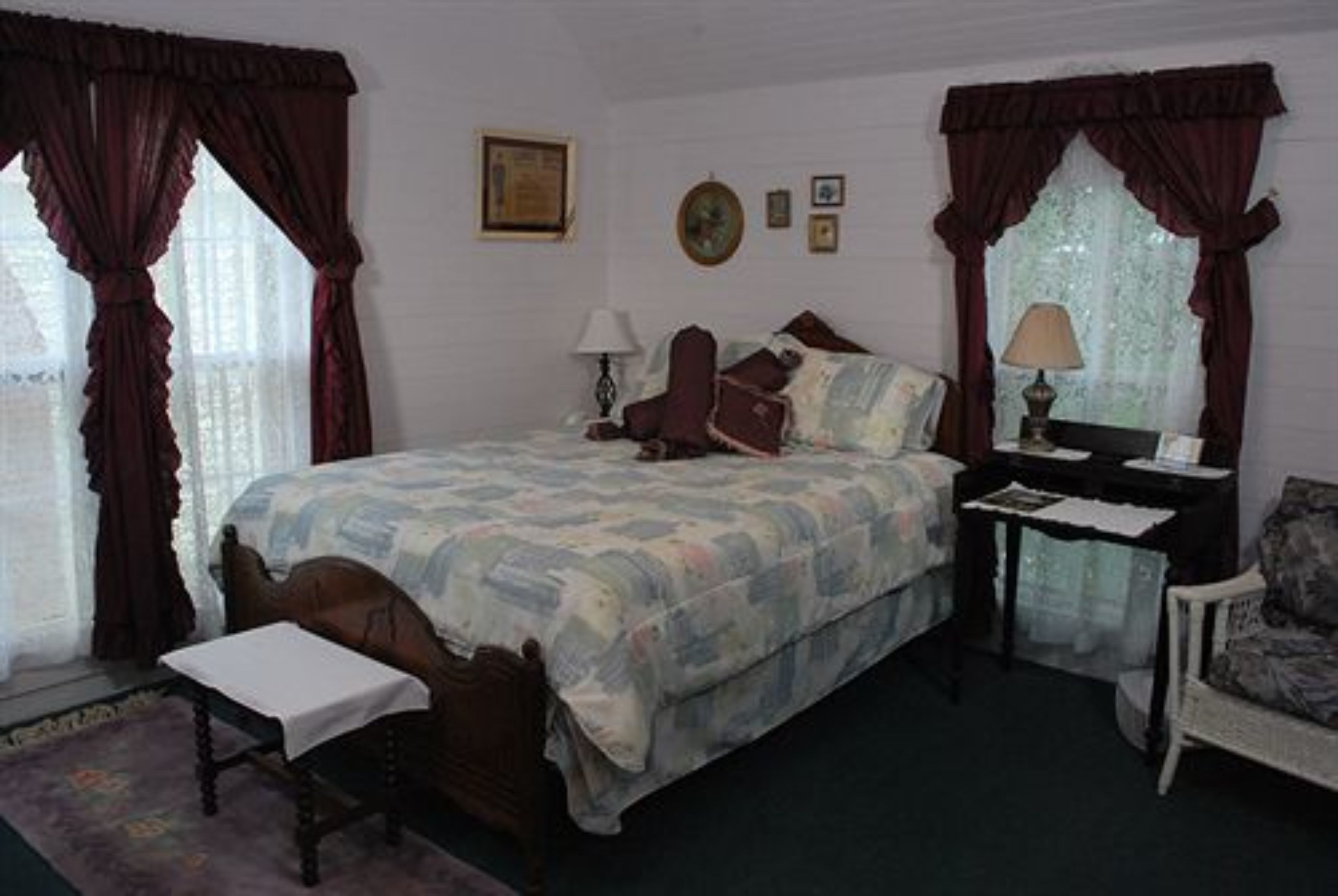 Un dormitorio con una cama grande, una mesita de noche, una silla y una ventana con cortinas.