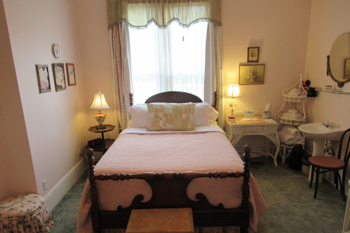 A bedroom with a bed, bedside tables, a chair, a small table, and a mirror.