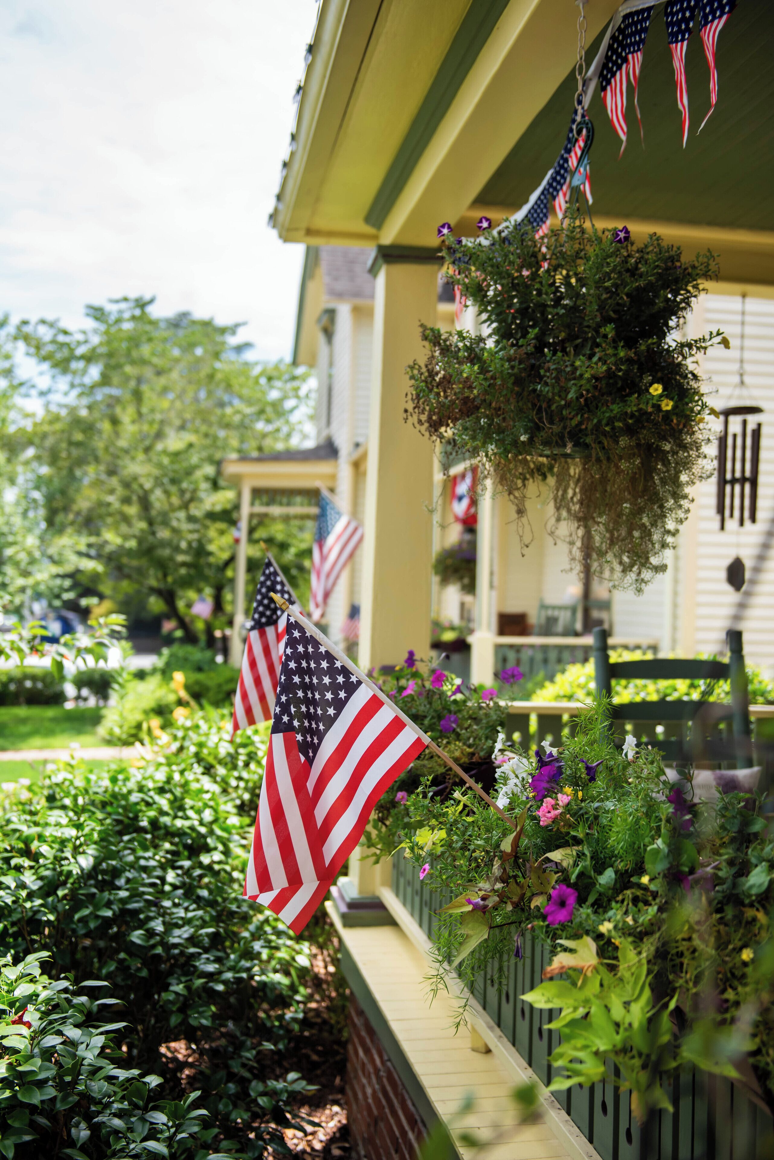 A house with American flags and hanging plants.