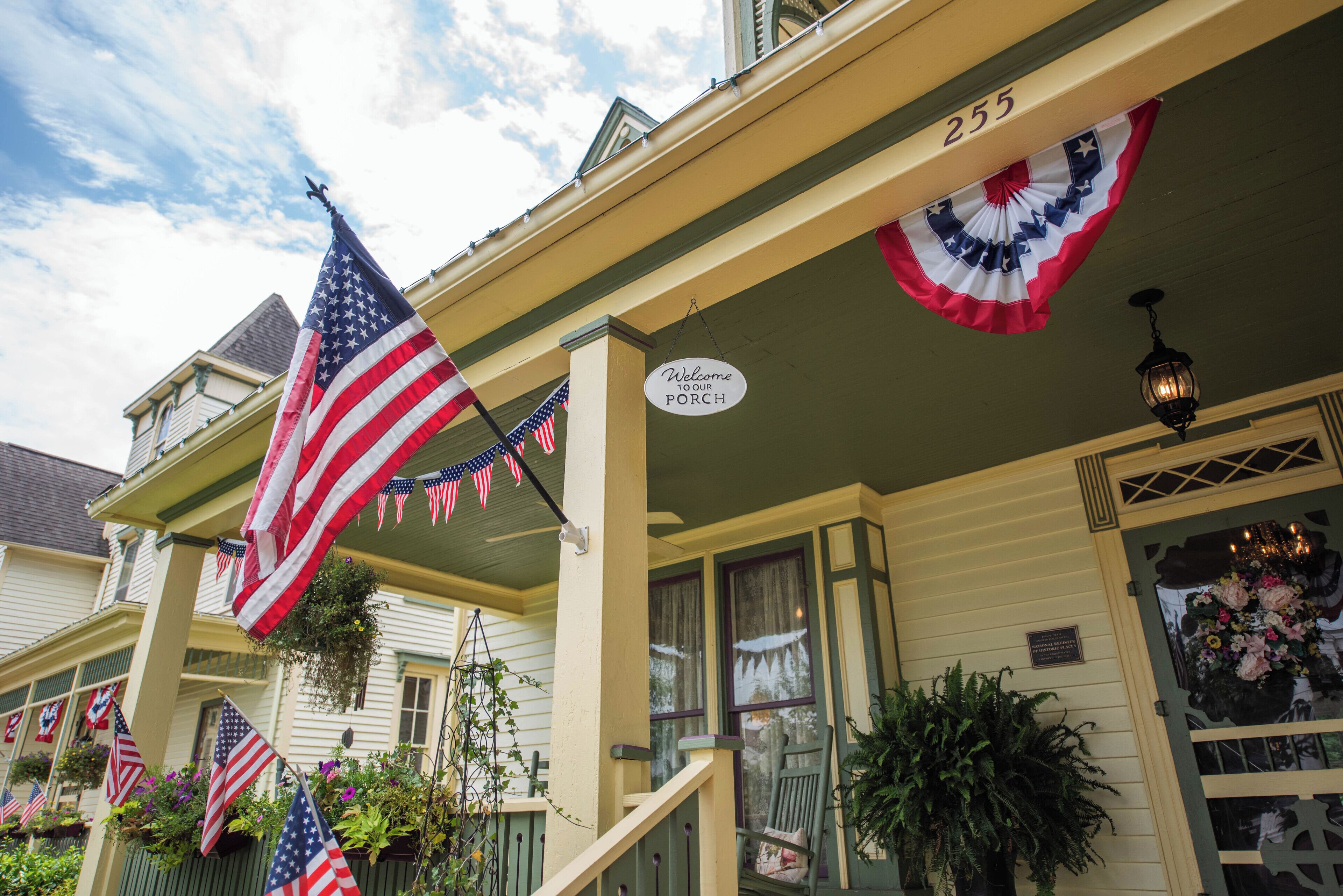 A house with a porch decorated with American flags and a welcome sign.