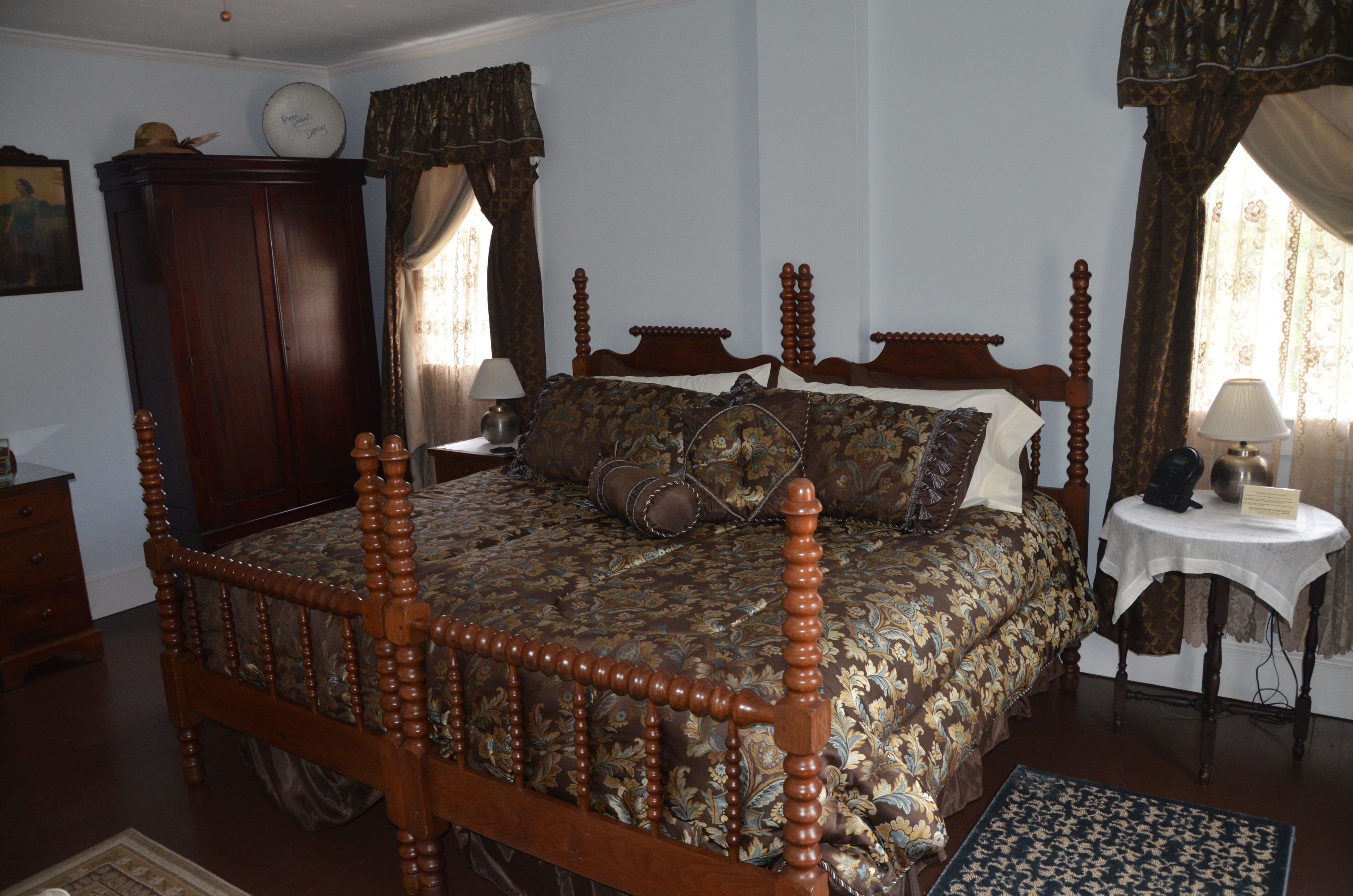 Un dormitorio tradicional con cama con dosel, un armario de madera y una mesita de noche con lámpara.