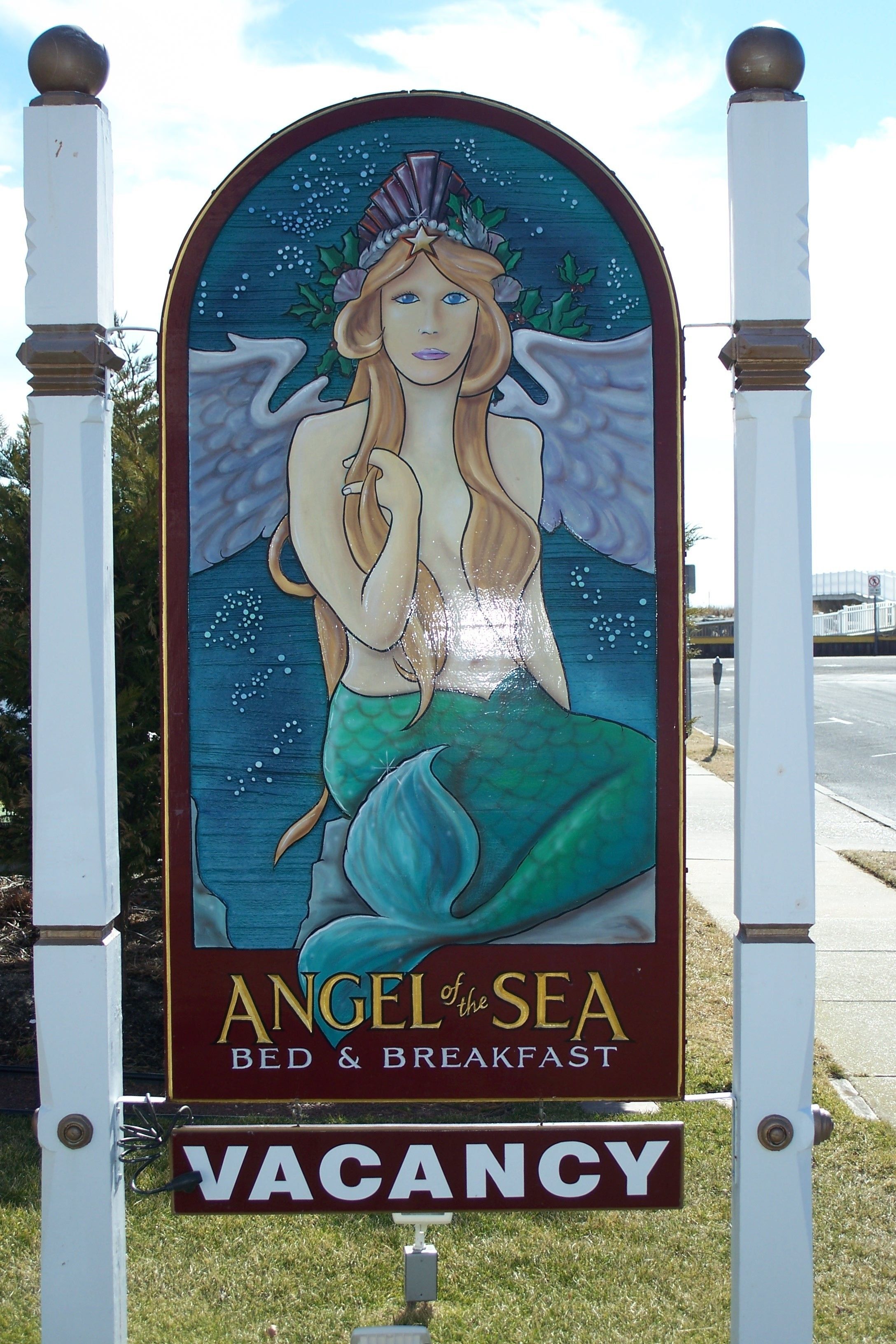 Une enseigne pour « Angel at the Sea Bed & Breakfast », avec une illustration de sirène et un avis indiquant qu’il y a des chambres disponibles.