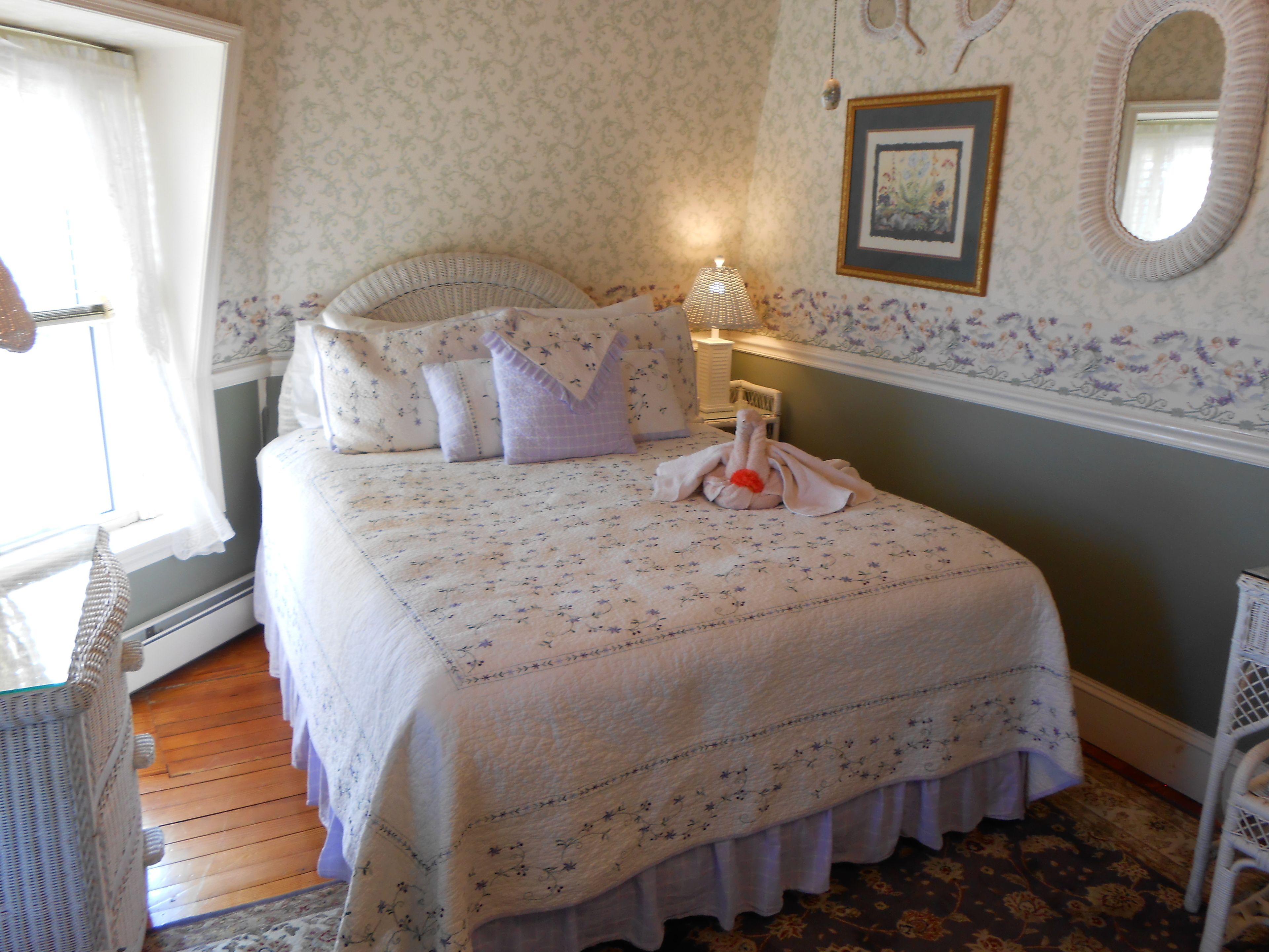A neatly made bed with floral bedding, a bedside lamp, and a framed picture on the wall.