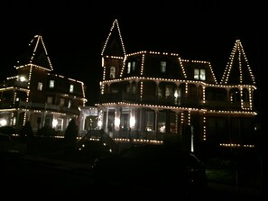 A large, illuminated building with multiple towers and a wrap-around balcony, likely a historic or landmark property. - Angel of the Sea (Cape May)